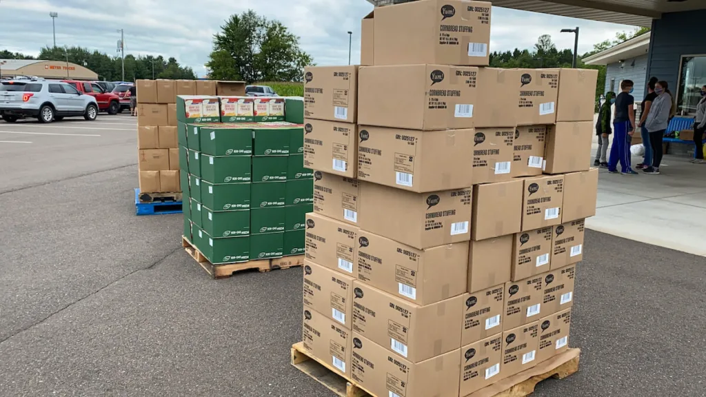 In this file photo from August 2020, recipients line up in their vehicles in a church parking lot in Cameron, WI, for surplus food from grocery stores.